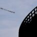 A plane towing a banner reading "MR MARA ENOUGH - PLZ FIX THIS DUMPSTER FIRE" flies over MetLife Stadium before the Giants-Saints game on Dec. 8, 2024.
