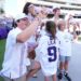 Blake Bonner, his wife Caitlin, and their children, with one daughter wearing a shirt with her late sister's name, on the field before a college football game.