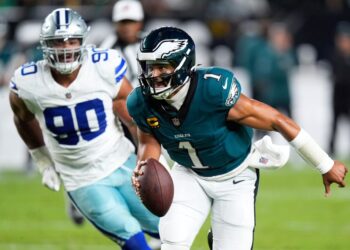 Jalen Hurts of the Philadelphia Eagles running with the football, pursued by Solomon Thomas of the Dallas Cowboys.
