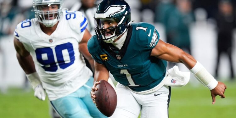 Jalen Hurts of the Philadelphia Eagles running with the football, pursued by Solomon Thomas of the Dallas Cowboys.