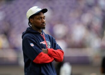 A New England Patriots player stands with his arms crossed.