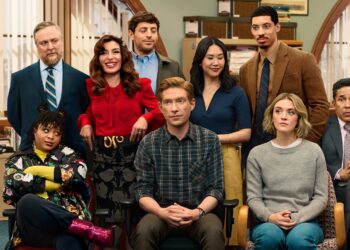 Four men and four women standing or sitting in an office together. The group appears to be posing for a group photo while they all look in different directions.