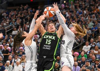 Three women's basketball players vying for the ball.