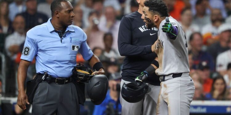New York Yankees third baseman Jose Caballero (72) is held back by manager Aaron Boone while arguing with home plate umpire Ramon de Jesus after a call during the fourth inning against the Houston Astros at Daikin Park.