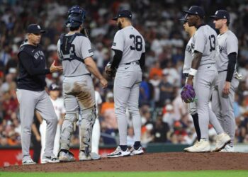 New York Yankees manager Aaron Boone and players confer on the pitcher's mound.