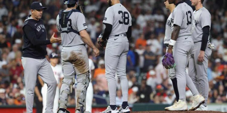 New York Yankees manager Aaron Boone and players confer on the pitcher's mound.