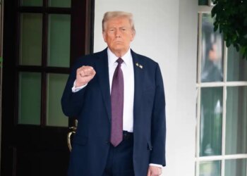 President Donald Trump stands with a clenched fist outside the White House.