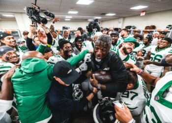 Aaron Glenn being lifted by Jets players in the locker room after their first win.