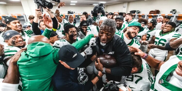 Aaron Glenn being lifted by Jets players in the locker room after their first win.