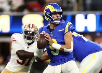 Matthew Stafford preparing to throw the football as Sam Okuayinonu approaches from behind.