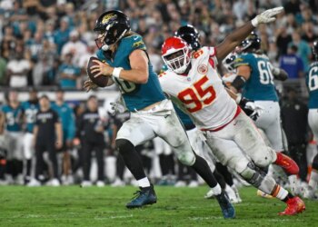 Jacksonville Jaguars quarterback Trevor Lawrence (16) running with the ball as Kansas City Chiefs defensive tackle Chris Jones (95) attempts to tackle him.