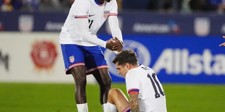 United States forward Tim Weah, left, helps up forward Christian Pulisic after he was injured against Australia in the first half of an international friendly soccer match Tuesday, Oct. 14, 2025, in Commerce City, Colo.