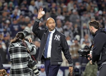 New York Yankees great Derek Jeter waves to the crowd as he walks out to throw the first pitch of the game before the start of tonightâs game.