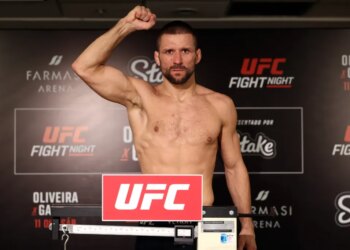 A man stands shirtless on a scale, flexing his right arm at the UFC Fight Night weigh-in.