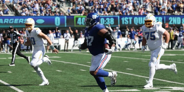 New York Giants defensive tackle Dexter Lawrence II (97) returns an interception as Los Angeles Chargers quarterback Justin Herbert (10) and Los Angeles Chargers center Bradley Bozeman (75) defend during the first quarter at MetLife Stadium.