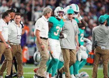 Miami Dolphins running back Ollie Gordon II (31) being helped off the field after an apparent injury.