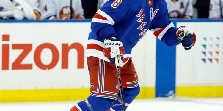 J.T. Miller of the New York Rangers skating on ice in front of the New York Islanders bench.