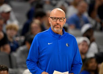 A male coach in a blue Dallas Mavericks jacket with a Nike swoosh.