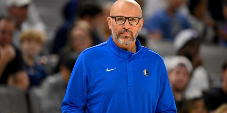 A male coach in a blue Dallas Mavericks jacket with a Nike swoosh.