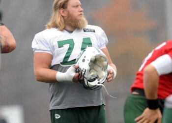 Nick Mangold, a football player with the number 74, at practice holding a helmet.
