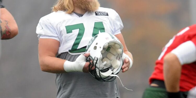 Nick Mangold, a football player with the number 74, at practice holding a helmet.