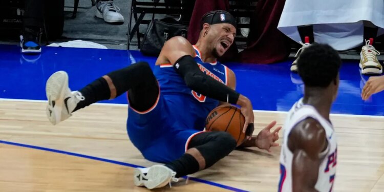 New York Knicks player on the ground holding a basketball.