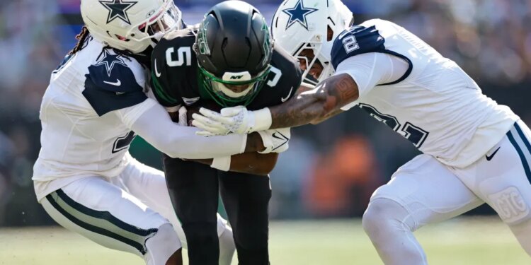 Two Dallas Cowboys players tackle a New York Jets player.