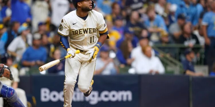 A baseball player in a white and gold "Brewers" uniform and number 11 running on a baseball field.