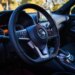 Interior of a Nissan Juke, showing the steering wheel with the Nissan logo, dashboard, and infotainment screen.