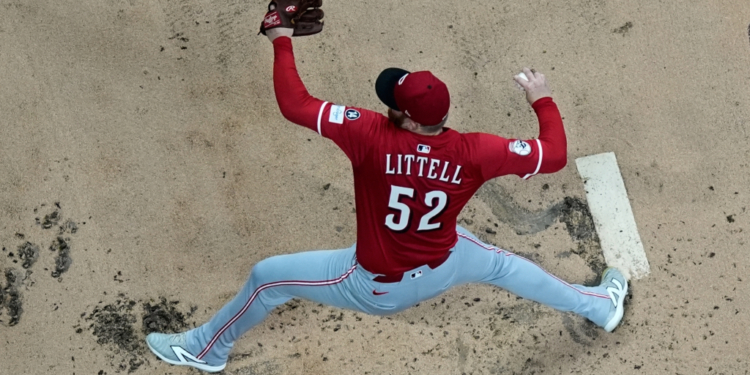 Baseball player Littell, number 52, wearing a red jersey, light gray pants, and a red cap, makes a throw from the pitcher's mound.