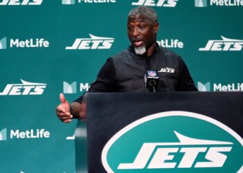 New York Jets head coach Aaron Glenn speaks at a podium.