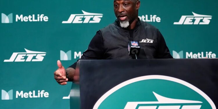 New York Jets head coach Aaron Glenn speaks at a podium.