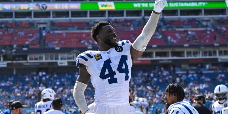 Indianapolis Colts linebacker Zaire Franklin points his finger up while standing on the sideline of a football field.