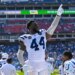 Indianapolis Colts linebacker Zaire Franklin points his finger up while standing on the sideline of a football field.