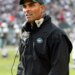 Herm Edwards, coach of the New York Jets, wearing a green cap and black jacket with a Jets logo.