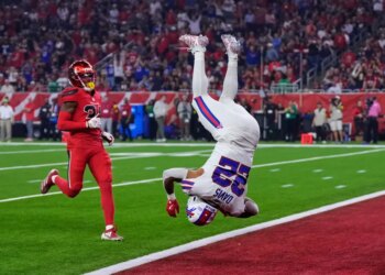 Buffalo Bills running back Ray Davis (22) in mid-air, having just returned a kickoff for a touchdown, as Houston Texans' Ajani Carter (21) looks on.