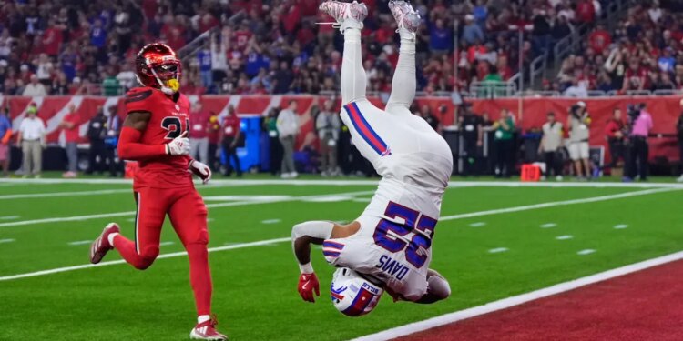 Buffalo Bills running back Ray Davis (22) in mid-air, having just returned a kickoff for a touchdown, as Houston Texans' Ajani Carter (21) looks on.