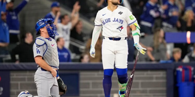 Toronto Blue Jays' Bo Bichette watches his three-run home run against the Los Angeles Dodgers as the Dodgers catcher kneels during Game 7 of baseball's World Series.