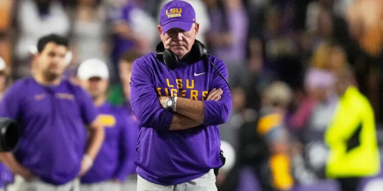 LSU head coach Brian Kelly standing on the sideline with his arms crossed.