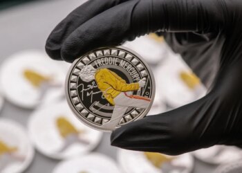 Gloved hand holding a Freddie Mercury coin.