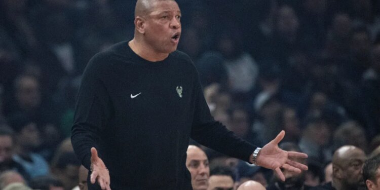 Doc Rivers on the court wearing a black long-sleeved shirt with the Bucks logo.