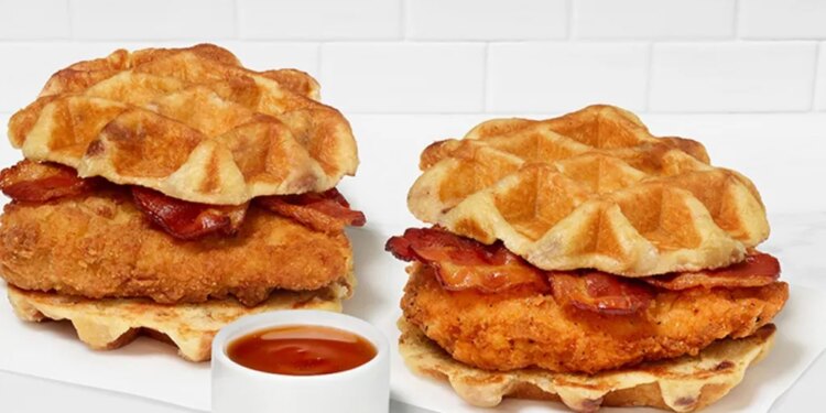 Two Chick-fil-A Waffle Breakfast Sandwiches with bacon and a side of sauce.