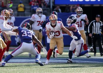 Christian McCaffrey #23 of the San Francisco 49ers running with the ball as Dru Phillips #22 of the New York Giants chases him.