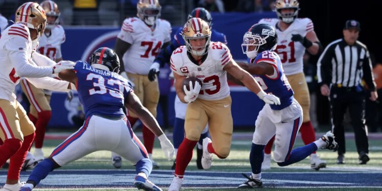 Christian McCaffrey #23 of the San Francisco 49ers running with the ball as Dru Phillips #22 of the New York Giants chases him.