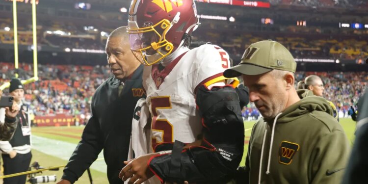 Washington Commanders quarterback Jayden Daniels (5) is helped off the field after an injury during the second half against the Seattle Seahawks.