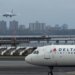 An American Airlines flight lands as a Delta Air Lines plane taxis at LaGuardia Airport in New York.