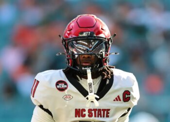 NC State Wolfpack quarterback CJ Bailey (11) in a red helmet and white jersey with a black facemask.