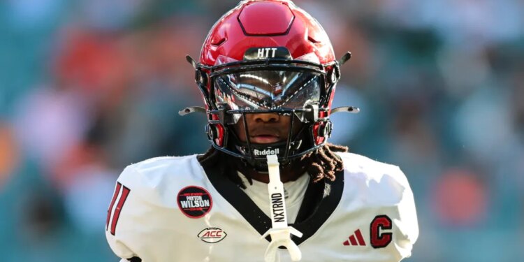 NC State Wolfpack quarterback CJ Bailey (11) in a red helmet and white jersey with a black facemask.