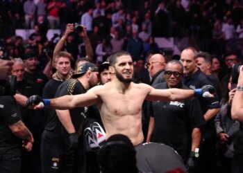 Islam Makhachev in blue gloves walks in before his welterweight championship bout at UFC 322.