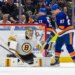 Boston Bruins goalie Jeremy Swayman making a save with New York Islanders player Anders Lee nearby.